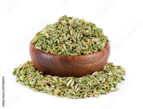Fennel seeds in wooden bowl, isolated on white background. Green fennel grains. Spices and herbs.