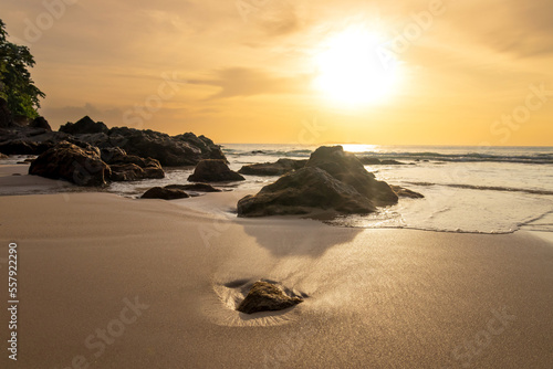 Beautiful sunset above sea. Vibrant and soft colors, reflection of sun in the sand on beach. Concept of romantic time on vacation in tropical.