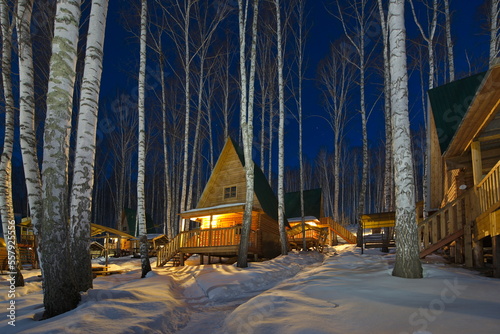 Russia. Krasnoyarsk Territory. Night view of guest houses in a birch grove on the shore of the lake Steam room rich in fish. This is an overnight stay for numerous fishermen.