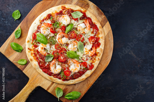 Traditionelle italienische Pizza frutti di mare Riesengarnelen, Tomaten und Mozzarella serviert als Draufsicht auf einer Pizza Schaufel aus Holz mit Textfreiraum 