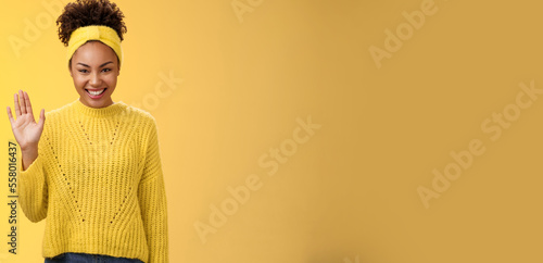 Cute timid friendly young girl wanna find new friends look pleasant smiling charmingly gladly waving hand hello hi gesture say welcome greeting heartwarming introduction herself, yellow background