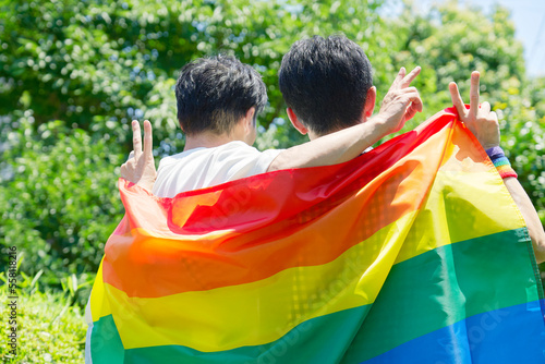 虹色の旗を持った性的マイノリティの男性カップルの後ろ姿