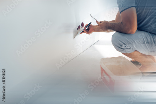 Plastering wall with putty-knife, close up image.