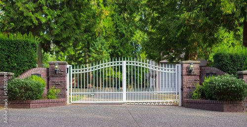 Double wrought-iron gate. Wrought iron gate and stone pillar. White wrought iron entrance gates to rural property