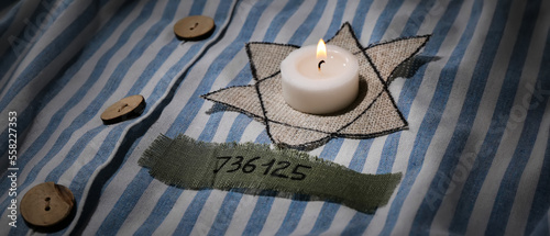 David star and burning candle on prisoner robe. International Holocaust Remembrance Day