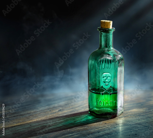 Glass poison bottle with skull and bones. Danger sign, symbol of death. Concept background on poison poisoning, chemistry, medical, old science topic. Poison, venom, toxin, toxic background.