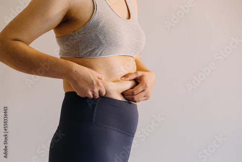 Beautiful fat woman with tape measure She uses her hand to squeeze the excess fat that is isolated on a white background. She wants to lose weight, the concept of surgery and break down fat under the