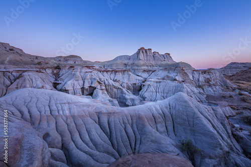 Barren badlands in the UNESCO World Heritage Site of Dinosaur Provincial Park in the blue hour before sunrise, Alberta Canada