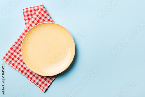 Top view on colored background empty round yellow plate on tablecloth for food. Empty dish on napkin with space for your design