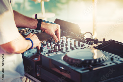 DJ is mixing music with deejay controller at outdoor summer pool party - nightlife people lifestyle concept