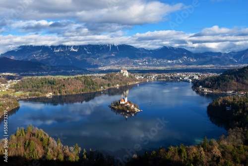 View of lake Bled and the church of the assumption on the island and Bled castle with cloud covered Karavanke mountains in winter in Gorenjska, Slovenia
