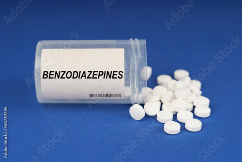 On a blue surface are pills and a dusty jar with the inscription - Benzodiazepines