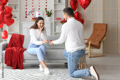 Young man proposing to his beloved girlfriend at home on Valentine's Day