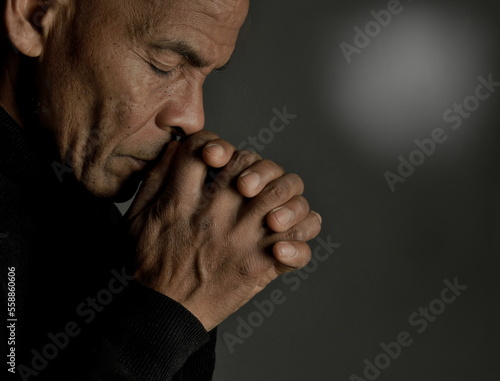 man praying to god at home on black background with people stock photo