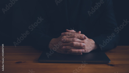 Christian life crisis prayer to god. man holding hands pray for god blessing to wishing have a better work and life on a wooden table. man hands praying to god with the computer. believe in goodness.