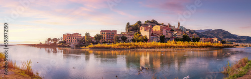 Old Residential Homes near river and sea in Ventimiglia, Italy. Fall Season. Sunset Sky Art Render. Panorama
