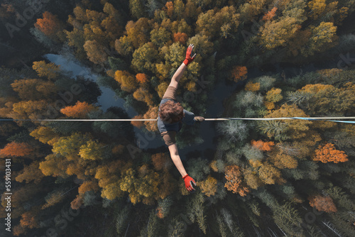 Highline over the forest. Rope walker walks on a rope at high altitude. Drone view. Slackline theme