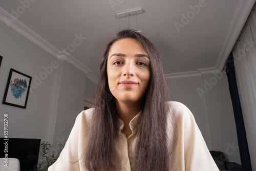 Woman looking at camera, head shot close up portrait of woman looking at camera. Laptop web cam view of businesswoman attending online meeting from home. Recording education video, consulting client.