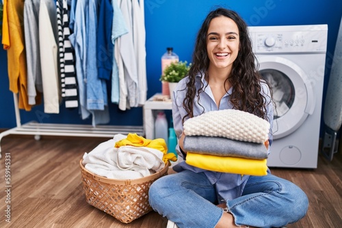 Young brunette woman holding clean laundry smiling and laughing hard out loud because funny crazy joke.