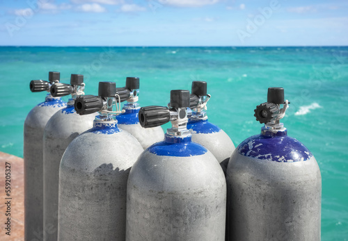 Close up picture of scuba tanks with turquoise water in the background, selective focus.