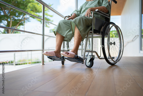 Old elderly disabled Asian patient or pensioner using wheelchair to practice to walk in nursing home in hospital. Senior people lifestyle activity recreation. Health care physical therapy