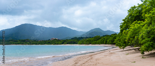 panorama of the famous conchal beach over the pacific in costa rica; paradise beach with turquoise water and green hills in the background