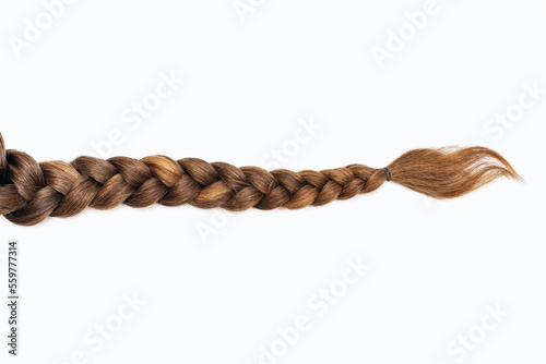 Female hair in the form of a braid on a white isolated background. Red hair braided close-up. Beautiful healthy natural female hair without dyeing