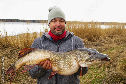 fisherman holding big pike fish. Northern Pike with beautiful natural camouflage. fishing in scandinavia.