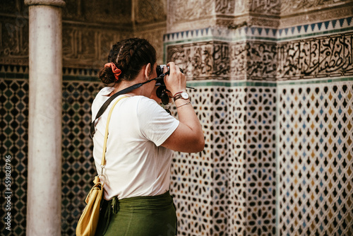 Turista Mujer con trenzas fotografiando azulejos árabes.