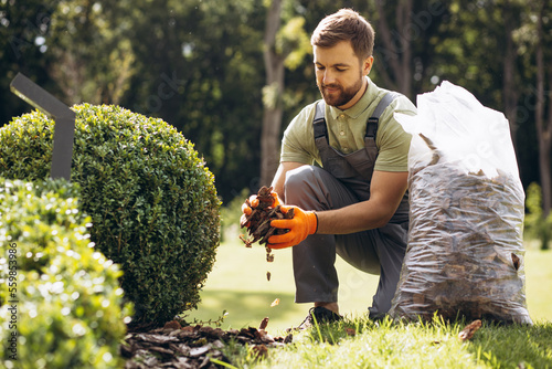 Gardner holding package of tree bark to cover the ground