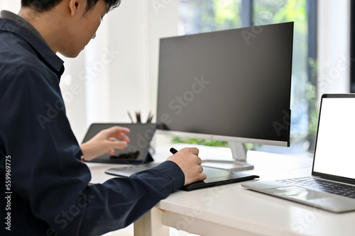 Focused Asian male programmer or web developer working at his office desk