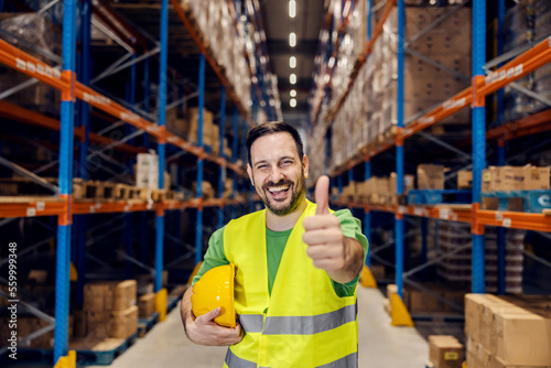 Portrait of a warehouse clerk smiling at the camera and giving thumbs up for full commodity reserves.