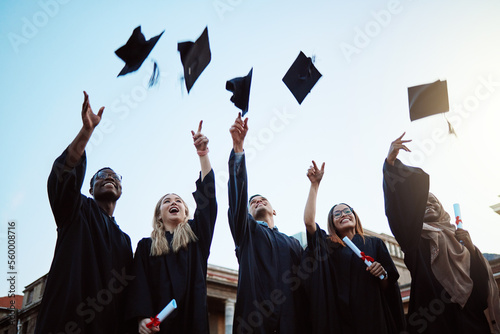 Graduation, education and success with friends in celebration as a graduate group outdoor, throwing mortar caps. Diversity, university and man and woman students celebrating a college diploma