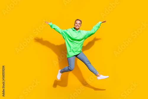 Full size photo of crazy cheerful girl have good mood jumping raise arms isolated on yellow color background