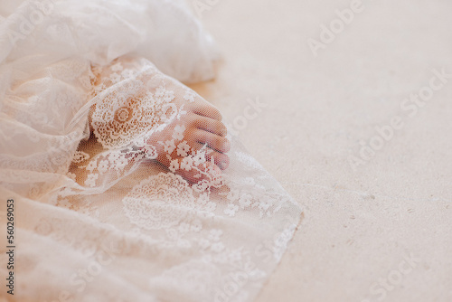 Pieds de jeune fille recouvert par le voile brodé de la mariée 