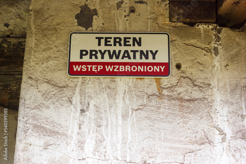 Stara , betonowa ściana , opuszczonego budynku przemysłowego z wiszącą nań tabliczką o treści : " TEREN PRYWATNY . WSTĘP WZBRONIONY " .
