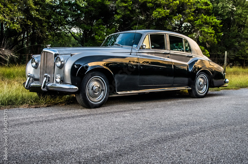 Two-toned, gray and black, classic, antique, luxury car on a rural road
