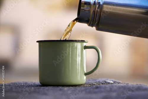 Pouring warm tea from a vacuum bottle into a cup