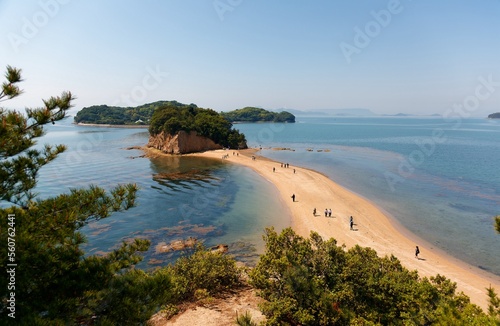 People walking on the Angel Road under blue sunny sky, a tidal sandbar connecting 3 beautiful offshore islets to Shodoshima Island in Seto Inland Sea and a tourist attraction in Tonosho, Kagawa, japan