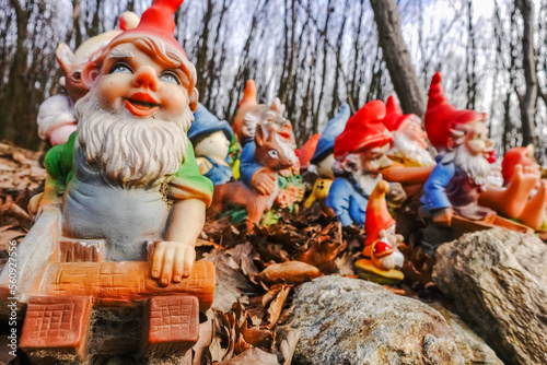 colorful garden gnomes with wood and saw at a place in the forest