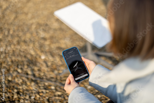 LVIV, UKRAINE - January, 2023: Woman holds phone with running Starlink application for installing satellite internet outdoors during sunny weather