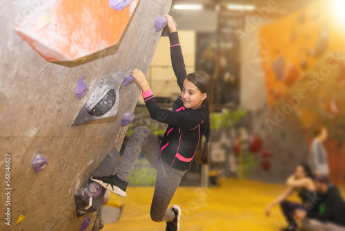 Teenage girl at indoor climbing wall. Kid having fun at bouldering wall. Child learning at climbing class. Sports healthy lifestyle. Youth at climbing summer camp