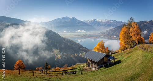 Colorful foggy morning in the Alps mountains. autumn foggy scenery. Amazing nature background. Mountainous autumn landscape. Red folliage on trees and fog in the distant valley. Zell am see lake