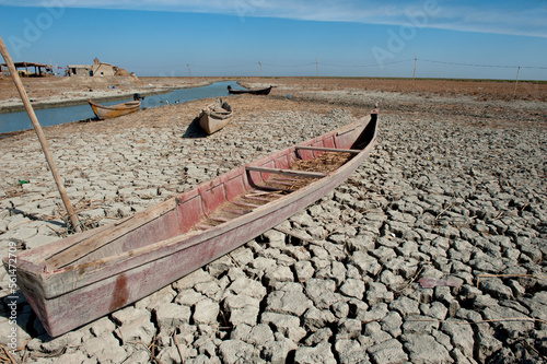 A traditional Marsh Arab canoe known as a Mashoof abandoned on the dry cracked earth of the southern marshes of Iraq during a hash summer drought. 