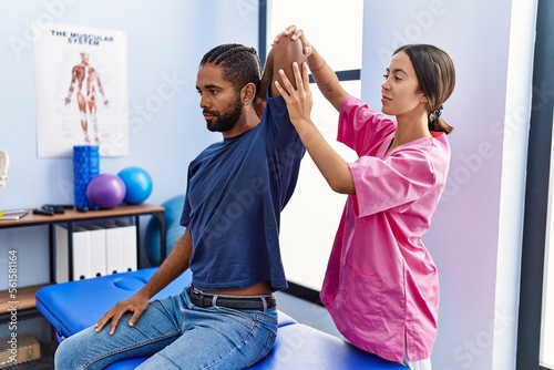 Man and woman wearing physiotherapist uniform having rehab session stretching arm at physiotherpy clinic