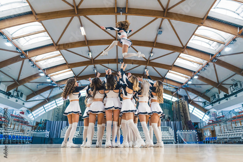 Full shot of a cheerleading squad hrowin one of their teammates high up in the air. Sport concept. High quality photo