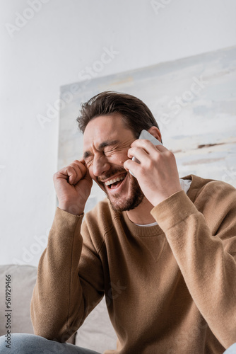 happy man with closed eyes talking on smartphone at home.