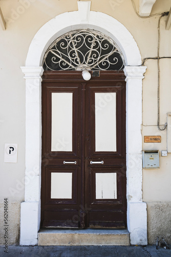 Old brown wooden front door in white stone arched doorway 