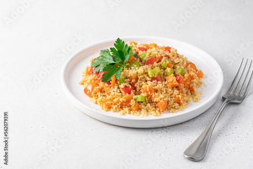 Quinoa with vegetables in a plate on a white background. Celery, carrots, paprika, tomato, parsley and quinoa seeds. Healthy diet balanced nutrition concept