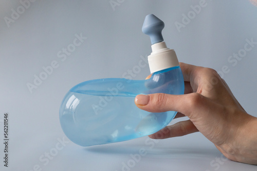 Neti Pot. Ayurvedic medical tools for cleaning your nose with water and salt at home. Blue bowl of water in a woman's hand